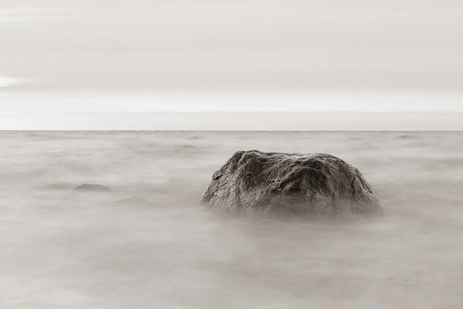 Fine art photography Baltic Sea by Ziggy Kańczukowski capturing a rock emerging from water with a blurred background.