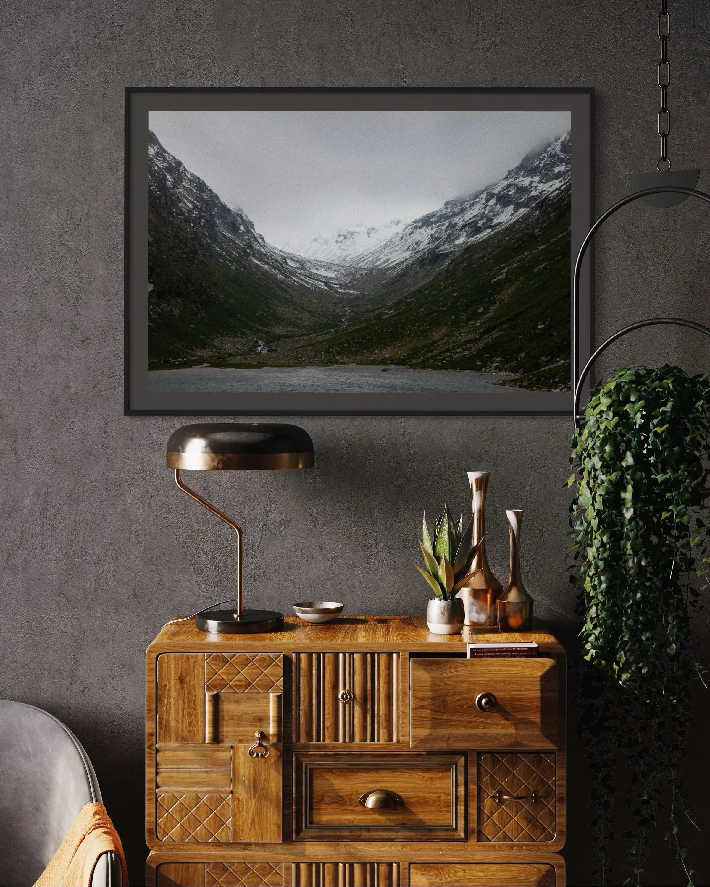 Framed fine art print High Tauern II by Ziggy Kańczukowski, depicting a mountain landscape, displayed above a wooden cabinet with decorative items.