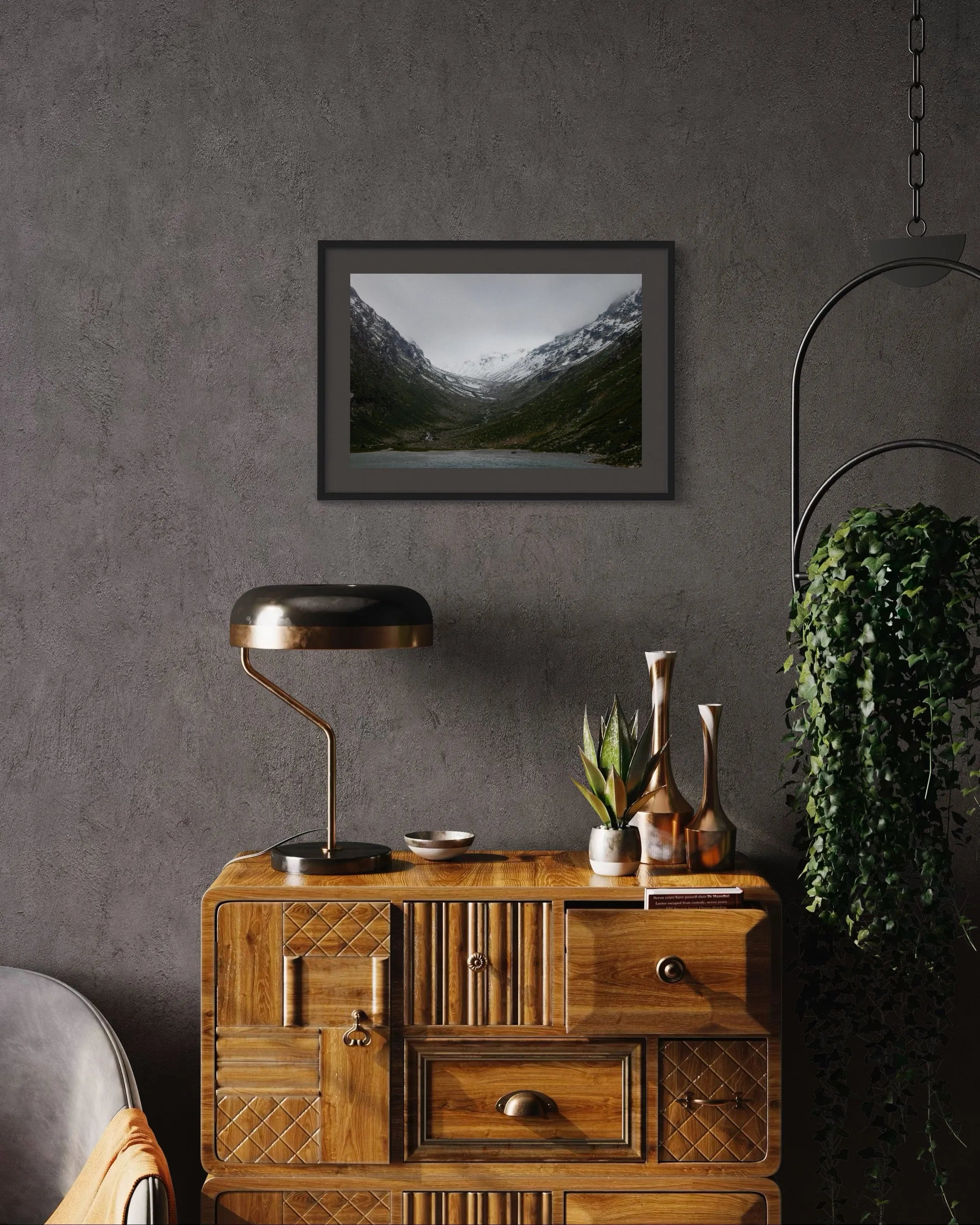 Framed fine art print High Tauern II by Ziggy Kańczukowski, depicting a mountain landscape, displayed above a wooden cabinet with decorative items.
