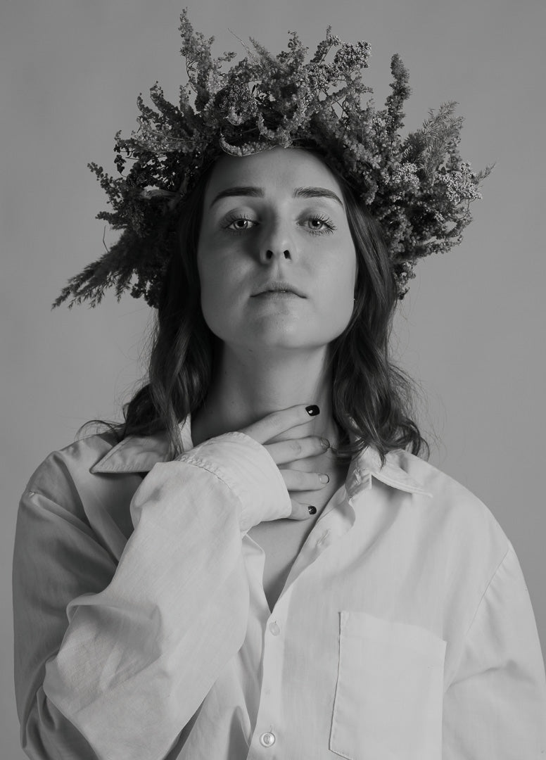 Black and white portrait of Oliwia Tomczak wearing a floral crown with a plain background