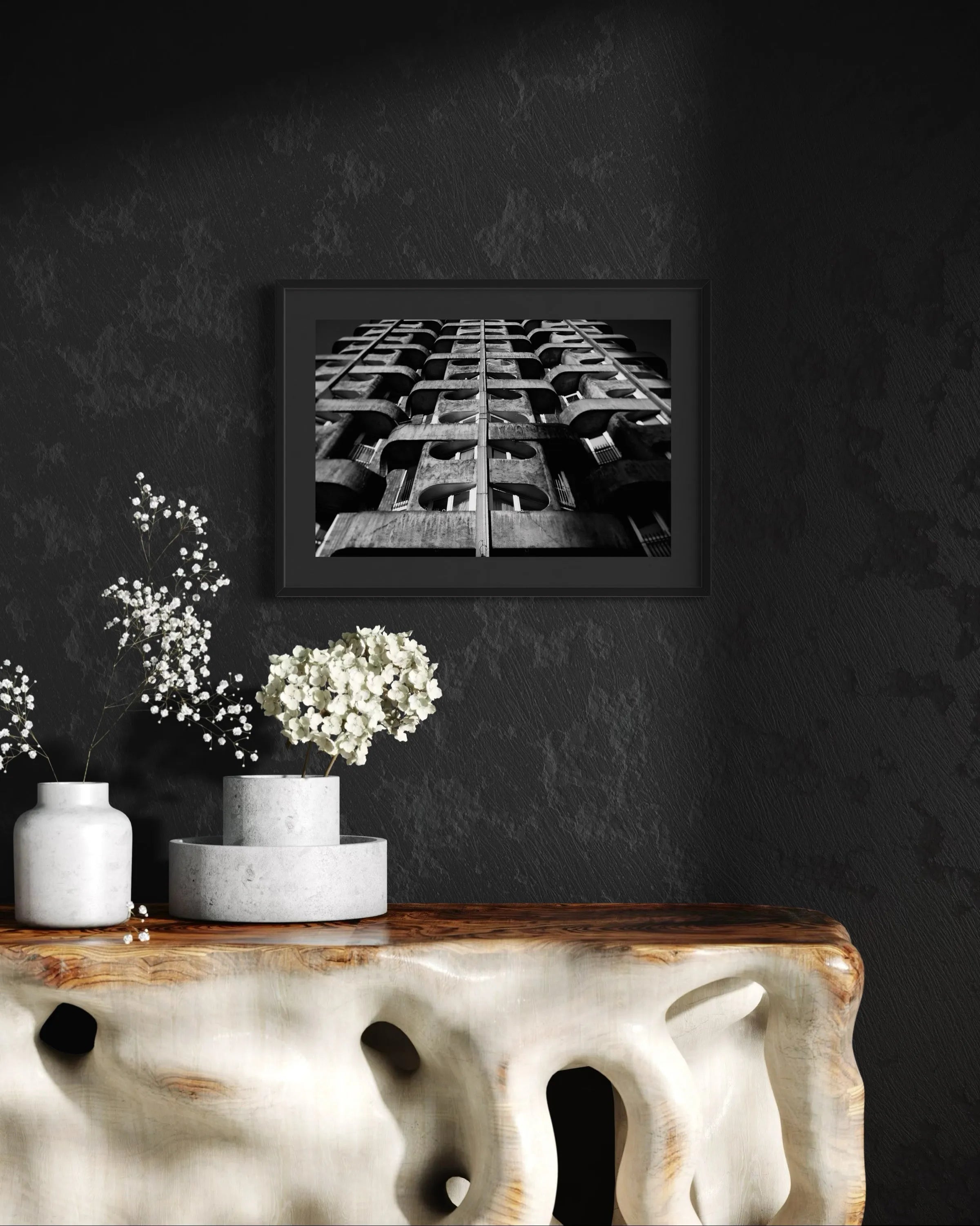 Framed black and white fine art print Structure 04 by Ziggy Kańczukowski displayed on a dark wall above a decorative table with flowers.