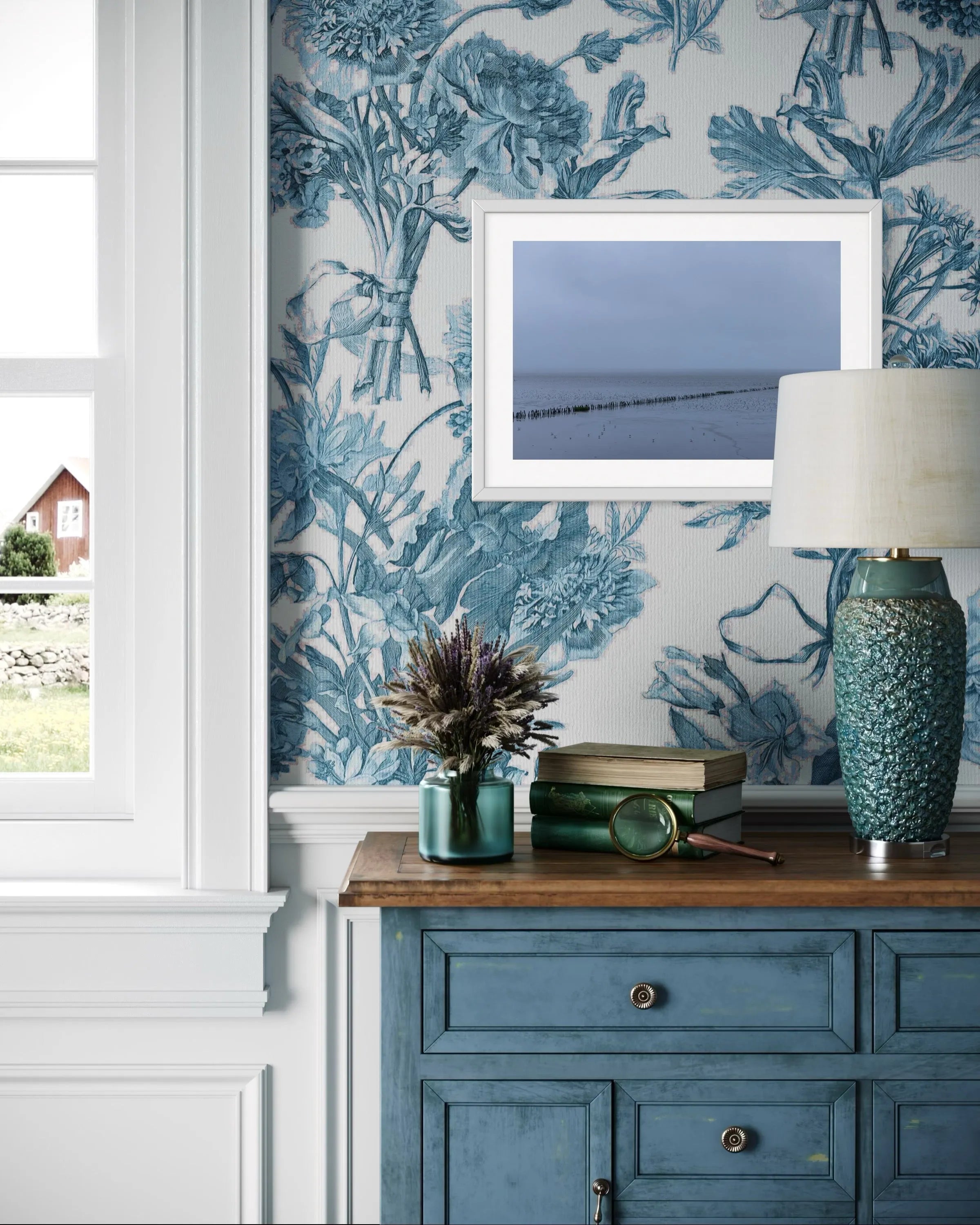 Framed fine art photography Wadden Sea by Ziggy Kańczukowski displayed in a room interior featuring blue floral wallpaper, a blue cabinet, and decorative items.
