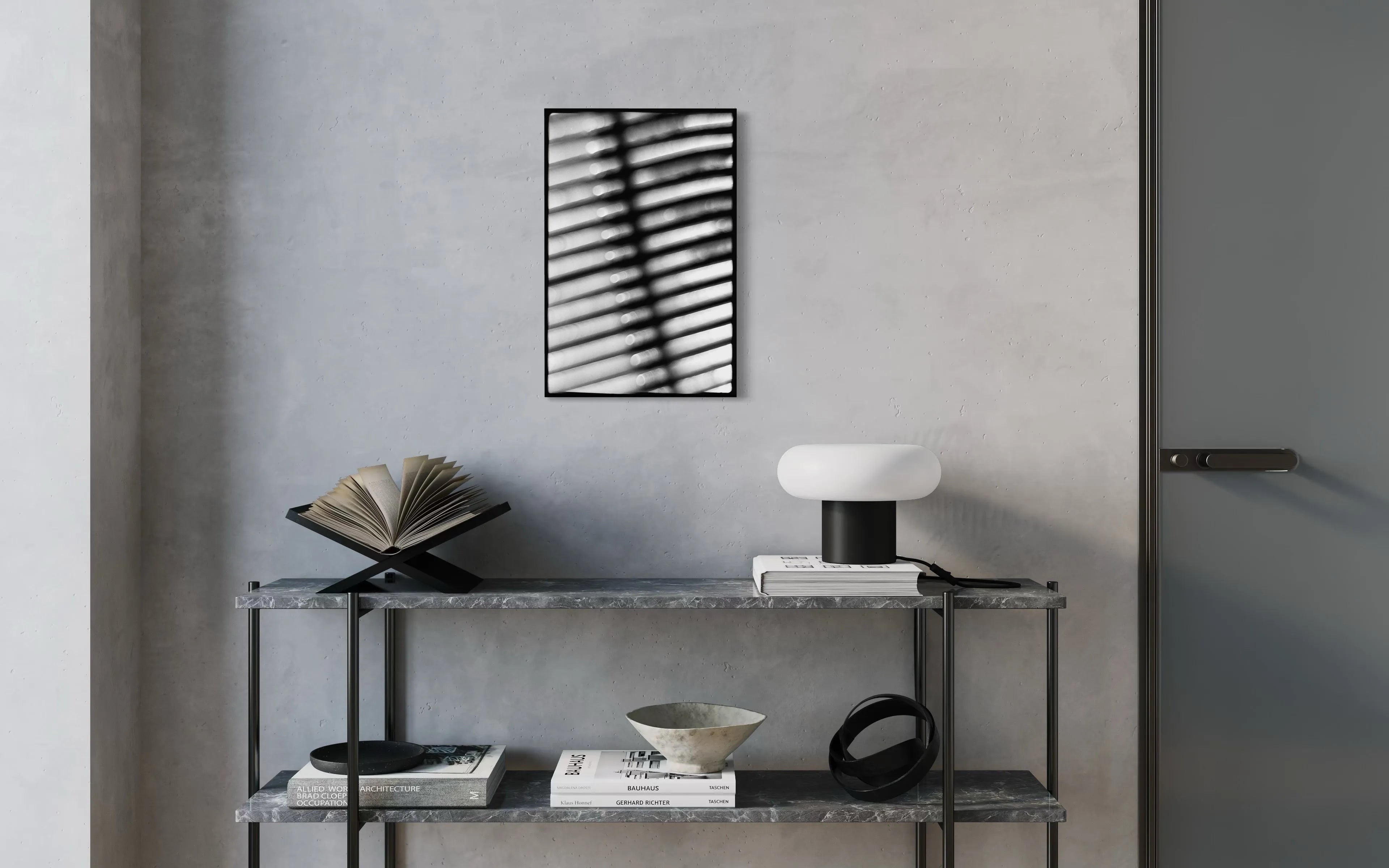Framed black and white fine art print Machine 06 by Ziggy Kańczukowski displayed on a shelf with books, a bowl, and a lamp against a gray wall in a modern interior.