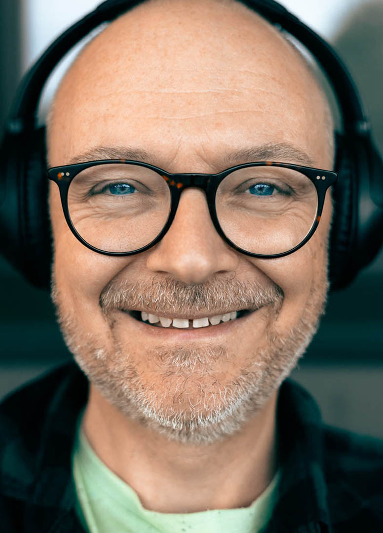 Zbigniew Kańczukowski wearing glasses and headphones with a blurred background
