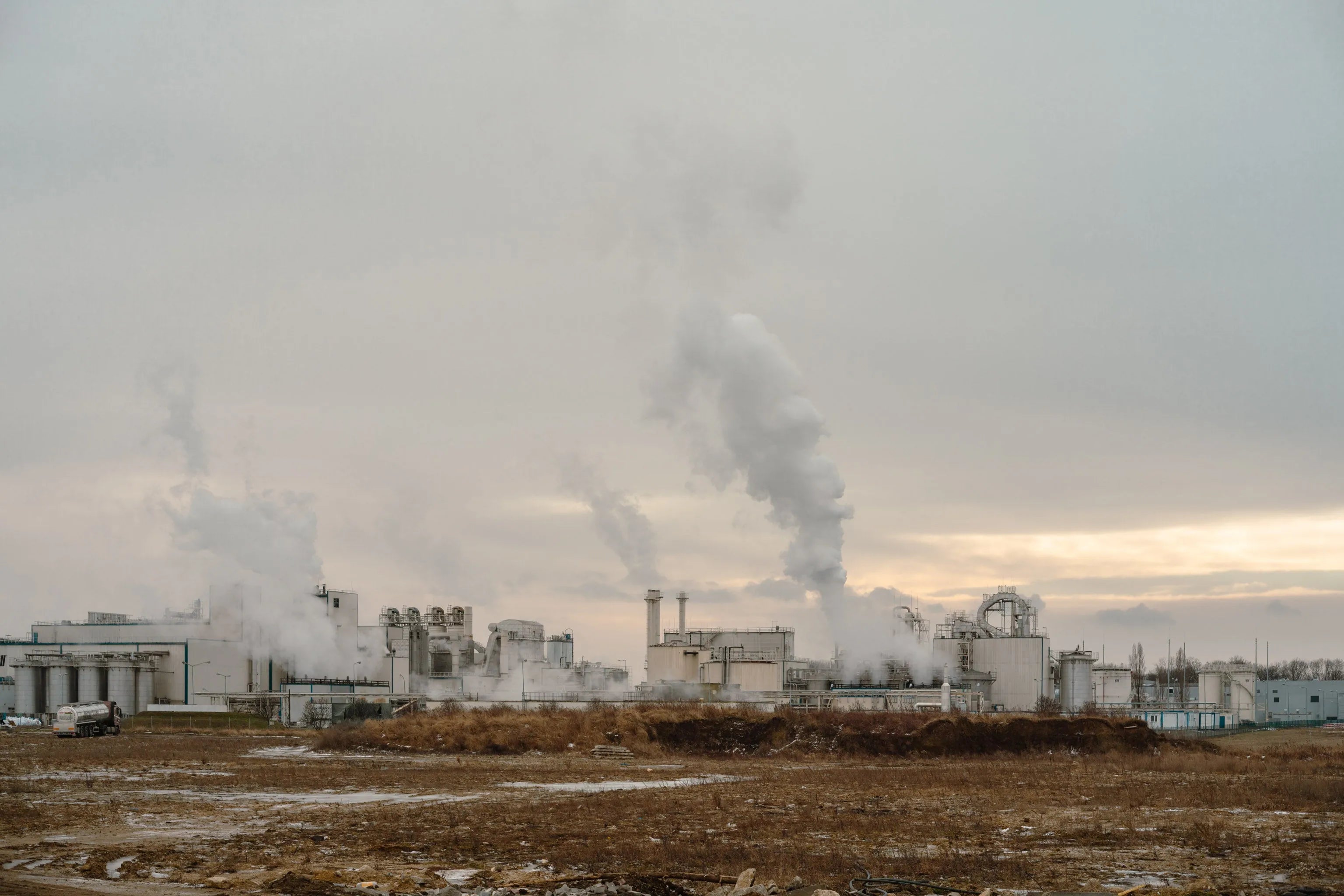 Fine art photography Smoke by Ziggy Kańczukowski capturing an industrial factory with smoke emissions against a cloudy sky.